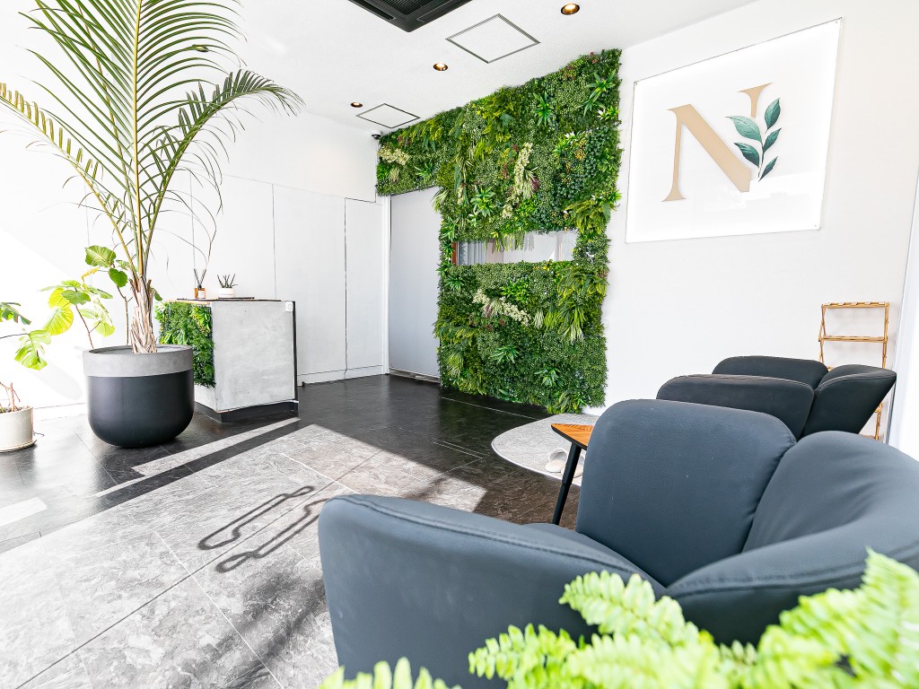 ダークトーンのソファとグリーンウォールのあるラウンジ・受付スペース。